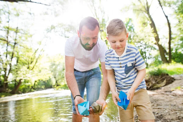 Junger Vater mit kleinem Jungen am Fluss, sonniger Frühlingstag. — Stockfoto