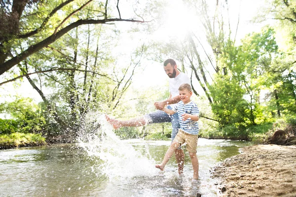 Nehirde, güneşli bahar günü küçük çocuk ile genç Baba. — Stok fotoğraf