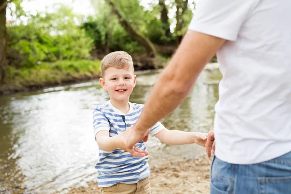 Mały chłopiec z ojcem nad rzeką, słoneczny dzień. — Zdjęcie stockowe