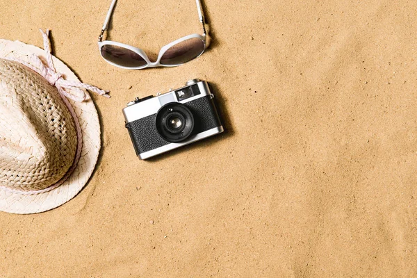 Gafas de sol, sombrero de mimbre y cámara. Fondo de arena . —  Fotos de Stock