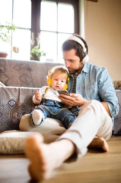 Padre e hijo con smartphone y auriculares, escuchando música . — Foto de Stock