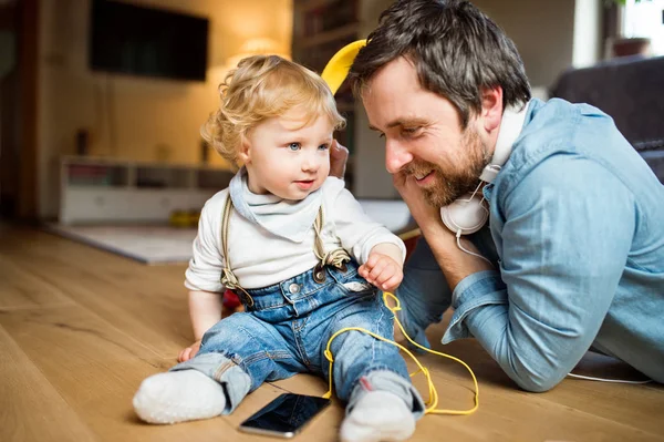 Padre e hijo con smartphone y auriculares, escuchando música . — Foto de Stock