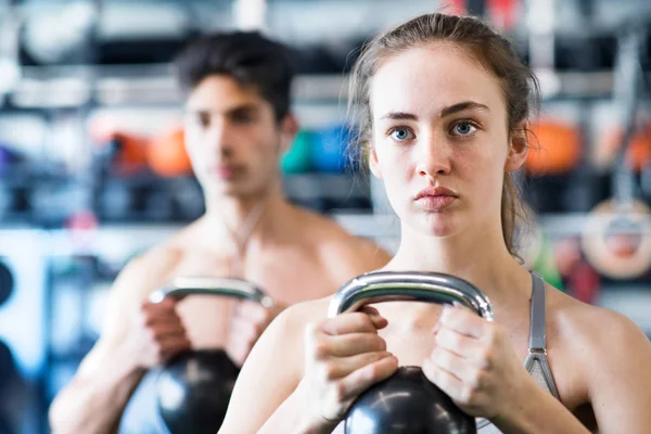 Fiatal pár alkalmas tornateremben edzés, kettlebell. — Stock Fotó