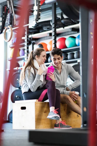 Hermosa pareja en forma joven en moderno gimnasio crossfit hablando . — Foto de Stock