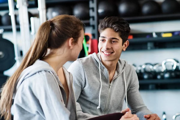 Hermosa pareja en forma joven en moderno gimnasio crossfit hablando . — Foto de Stock