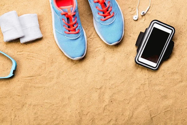 Chaussures de sport, écouteurs, smartphone contre le sable, plan studio . — Photo