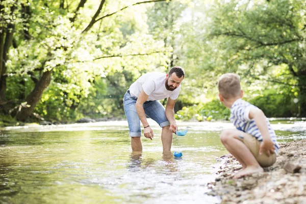 Padre joven con niño en el río, día soleado de primavera . — Foto de Stock