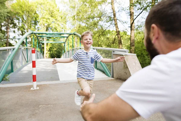 Niño corriendo a los brazos de padre, día soleado de verano . — Foto de Stock