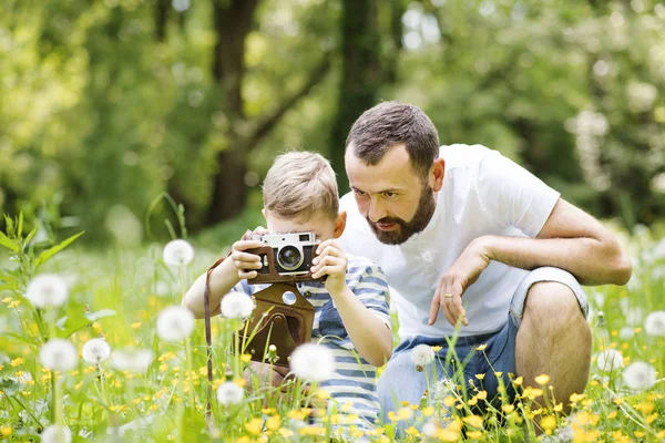 Mladý otec s malým chlapcem s kamerou v letním parku. — Stock fotografie