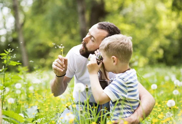 Padre joven con niño pequeño con cámara en el parque de verano . — Foto de Stock