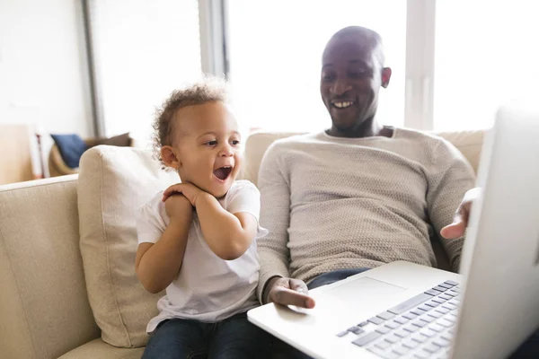 Afro-amerykański ojca z córeczką w domu trzymając laptop. — Zdjęcie stockowe