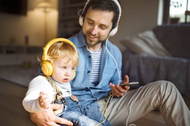 Baba ve oğul ile akıllı telefon ve kulaklık, müzik dinleme.