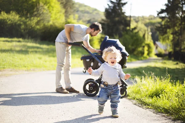 Vader met dochtertje zoon en baby in kinderwagen. Zonnige park. — Stockfoto