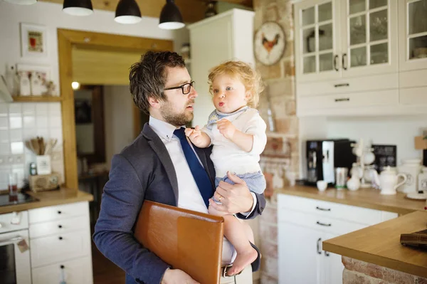 Homme d'affaires rentrant à la maison, tenant son petit fils dans les bras . — Photo