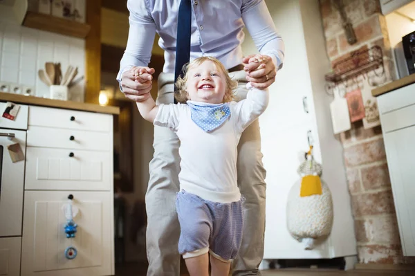 Oigenkännlig far håller händerna på hans son tar första stegen. — Stockfoto