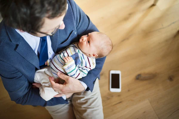 自宅のビジネスマンが腕の中で赤ん坊の娘を保持. — ストック写真