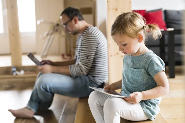 Ayah dengan laptop dan putri kecil dengan tablet di rumah . — Stok Foto