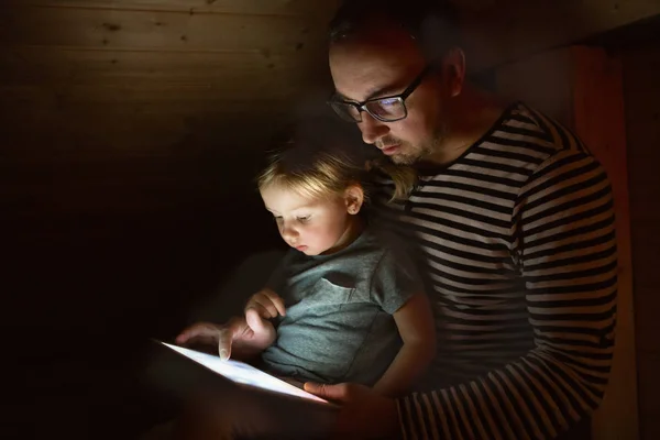 Padre con tableta e hija pequeña en casa por la noche . — Foto de Stock