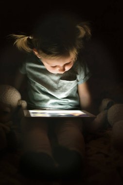 Kız evde gece tablet bir şey izlerken.