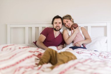 Sevimli küçük çocuklarıyla birlikte yatakta genç anne