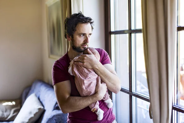 Jovem pai em casa segurando seu bebê recém-nascido menina . — Fotografia de Stock