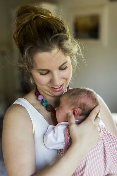 Joven madre en casa sosteniendo a su hija recién nacida —  Fotos de Stock