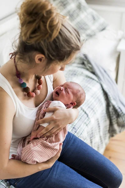 Jovem mãe em casa segurando sua filha recém-nascida — Fotografia de Stock
