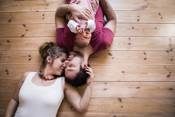 Ouders houden hun schattige baby dochter, houten achtergrond. — Stockfoto