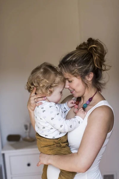 Joven madre en casa sosteniendo a su lindo hijo pequeño — Foto de Stock