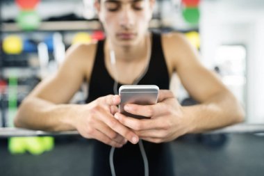 Dinlenme, akıllı telefon tutarak, müzik dinleme spor salonunda İspanyol adam