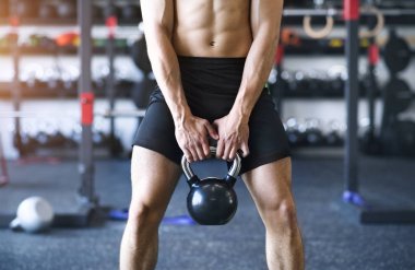 Tanınmayan genç adam kettlebell ile egzersiz spor salonunda yerleştirmek.