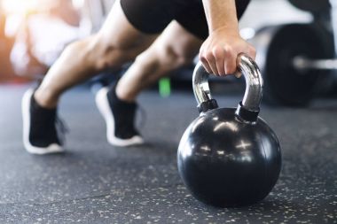 Tanınmayan uygun adam gönderme yapıyor spor salonunda ups kettlebells üzerinde
