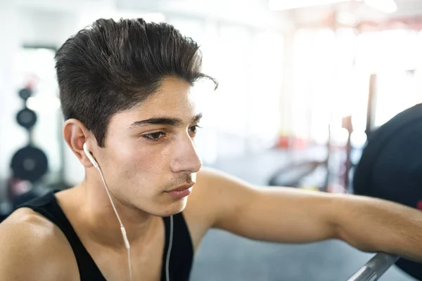 Spansktalande mannen i gym vila, hörlurar i öronen, lyssna mus — Stockfoto