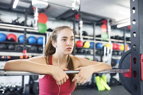 Ung kvinna i gym, hörlurar i öronen, lyssnar musik — Stockfoto