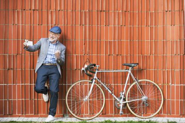 Üst düzey adam akıllı telefon ve duvara karşı Bisiklet.