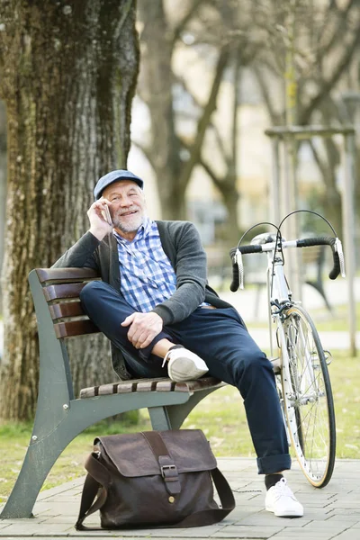 Uomo anziano con bicicletta e smartphone, fare telefonate — Foto Stock