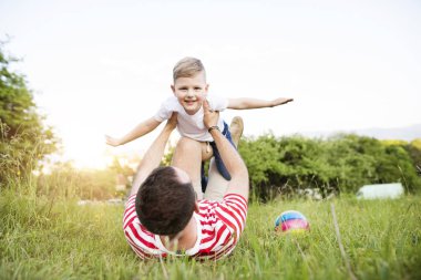 Hipster baba ve küçük oğlu yeşil çayır üzerinde. Güneşli yaz gün.