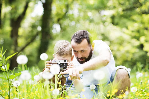 Mladý otec s malým chlapcem s kamerou v letním parku. — Stock fotografie