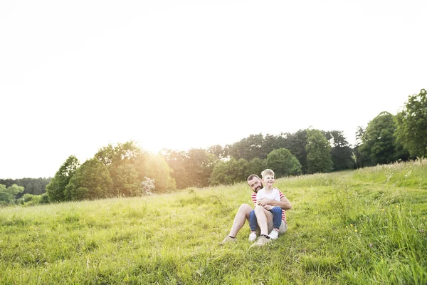 Отец-хипстер и маленький сын на зеленом лугу. Солнечный летний день . — стоковое фото