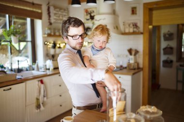 Genç baba evde küçük oğluyla birlikte bisküvi yemek.