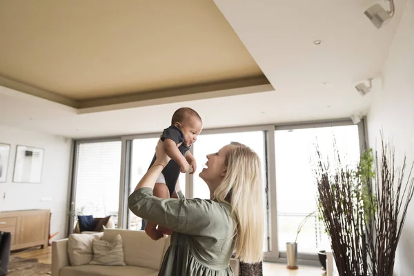 Vacker ung mor med sin lilla baby pojke hemma. — Stockfoto