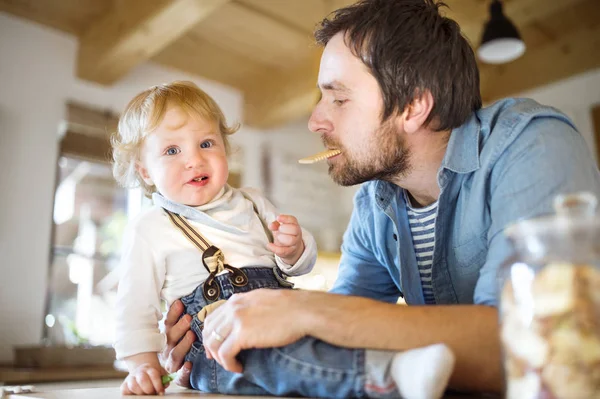 Genç baba evde küçük oğluyla birlikte bisküvi yemek. — Stok fotoğraf
