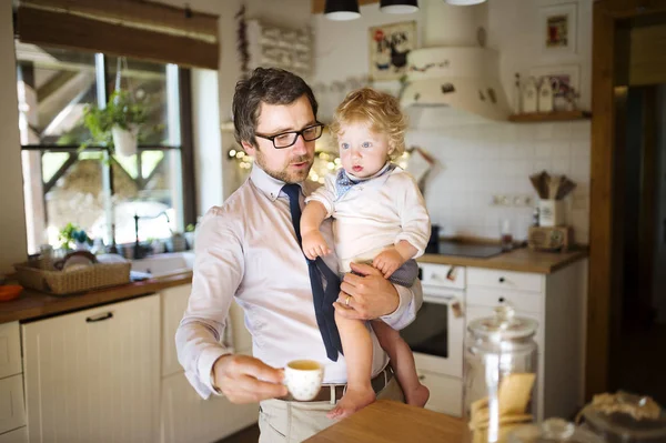 Geschäftsmann hält kleinen Sohn in den Armen, trinkt Kaffee. — Stockfoto