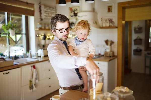 Young father at home with his little son eating biscuit together. — Stock Photo, Image