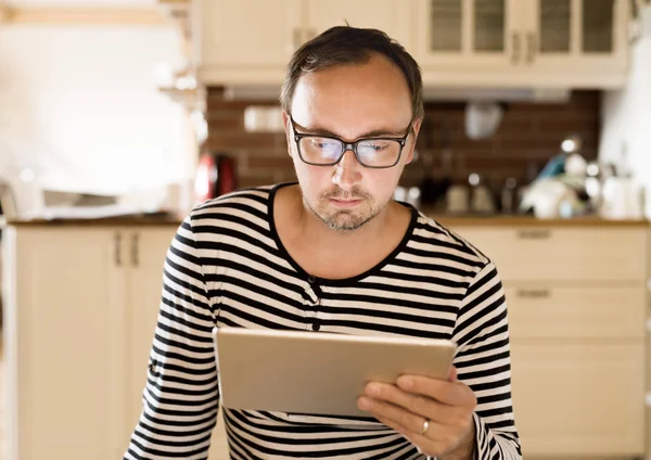 Νεαρός άνδρας σε ριγέ μπλουζάκι με tablet στο σπίτι. — Φωτογραφία Αρχείου