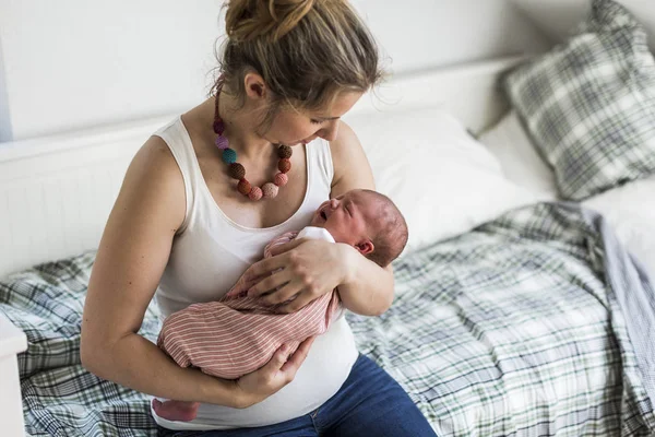 Joven madre en casa sosteniendo a su hija recién nacida — Foto de Stock