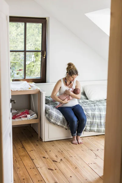 Young mother at home holding her newborn baby daughter — Stock Photo, Image
