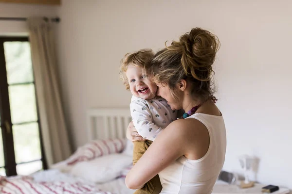 Young mother at home holding her cute little son — Stock Photo, Image