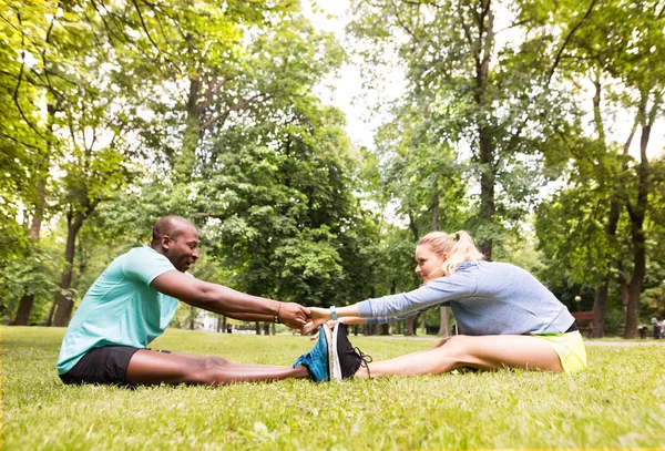 Correndo casal alongamento e aquecimento no parque antes do treinamento — Fotografia de Stock