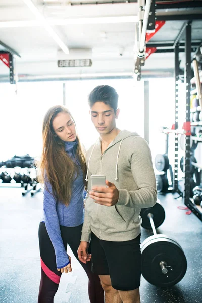 Adatta alla coppia in una moderna palestra crossfit con smartphone . — Foto Stock